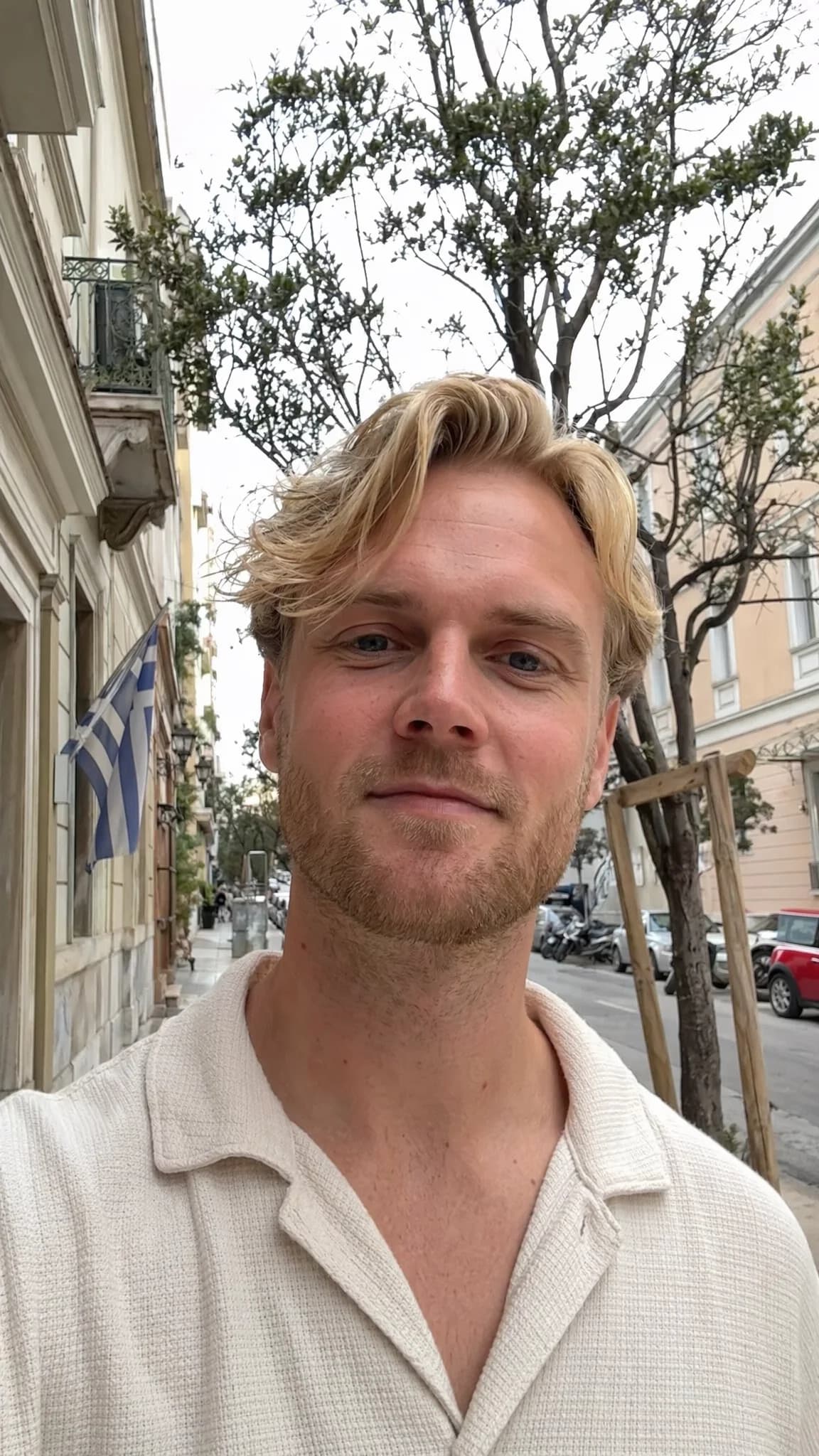 Realistic AI selfie portrait of a blond man on a city street